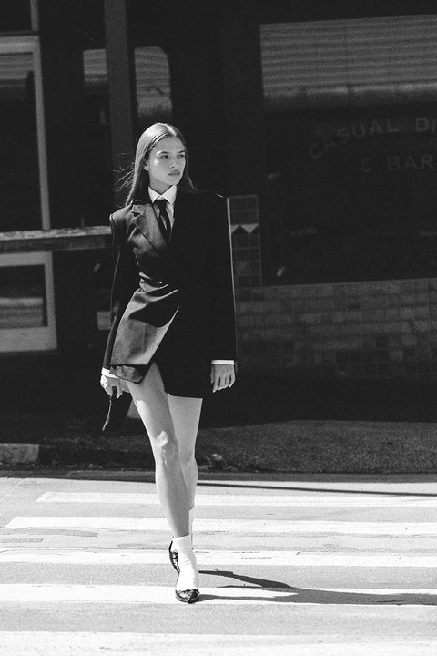 Woman in a vintage outfit, holding a Lip Combo Bag while crossing a street.