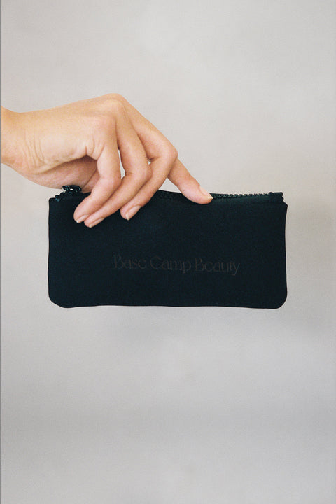 Black Lip Combo Bag with 'Base Camp Beauty' branding held by a hand on a light background