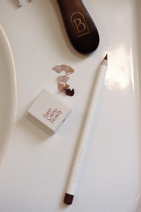 Makeup pencil and sharpener on a white surface.